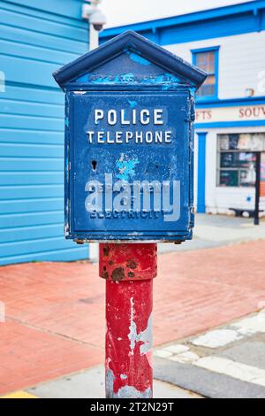 Cavalletto per telefono vintage Police su palo rosso con scatola blu di fronte al negozio Foto Stock