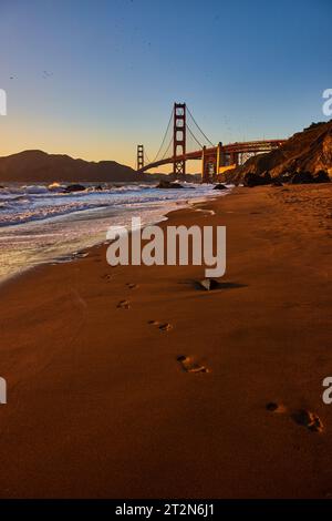 Impronte di sabbia provenienti dalle onde che si infrangono al tramonto con il Golden Gate Bridge Foto Stock