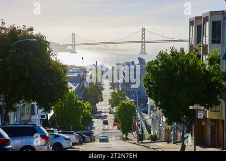 Soleggiata vista in cima a una collina del ponte Oakland Bay dalla strada cittadina con un'auto che arriva dall'hotel Foto Stock