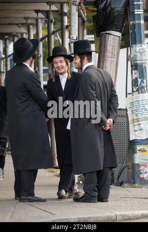 Tre ebrei chassidici con piselli lunghi e ricci fanno una conversazione divertente su Lee Avenue a Williamsburg, Brooklyn, New York Foto Stock