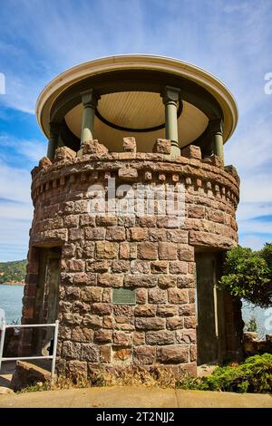 Lyfords Stone Tower sotto il cielo blu nuvoloso incorniciato dall'oceano e dalla costa lontana Foto Stock