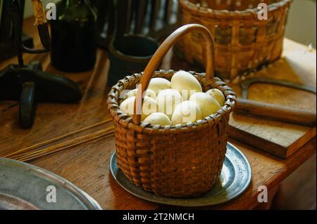 Uova di gallina raccolte in un cestino poggiato su un tavolo di legno Foto Stock