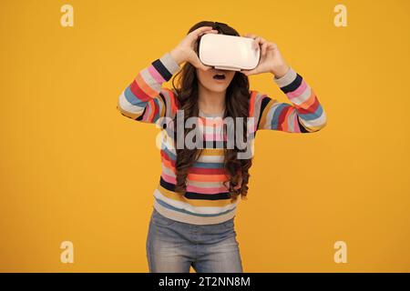 La ragazza adolescente tiene occhiali vr utilizzando la tecnologia futura per l'istruzione, scuola di realtà virtuale. Divertente adolescente che gioca a giochi per 3D in realtà aumentata. Faccia stupita scioccata Foto Stock