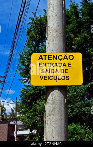 Cartello di avvertimento in portoghese che informa "attenzione, ingresso e uscita dei veicoli", Ribeirao Preto, San Paolo, Brasile Foto Stock