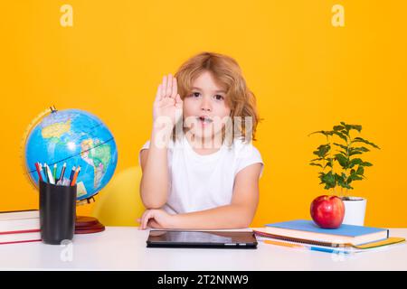 Bambino della scuola che alza le mani, disposto a rispondere alla domanda. Scuola e bambini. Bambino biondo cute con un libro che impara. Giornata della conoscenza. Foto Stock