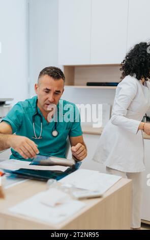 Medico esperto che discute di diagnosi di salute con giovane paziente maschio Foto Stock
