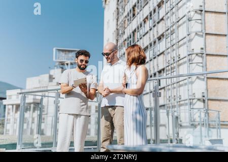 Un gruppo di professionisti discute un progetto all'aperto per un progetto di costruzione in città. Collaborano, risolvono i problemi e stimano i costi. Foto Stock