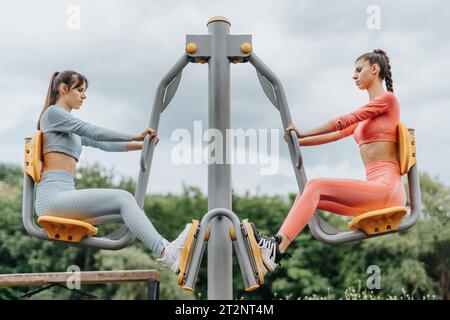 Un gruppo di ragazze sportive in forma e motivate si allenano all'aperto in un parco cittadino, ispirando uno stile di vita sano e attivo. Foto Stock