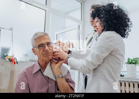 Professionisti sanitari esperti che conducono esami medici approfonditi per pazienti anziani in clinica Foto Stock