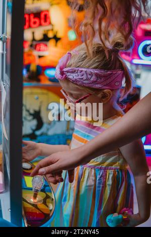 Una bambina che gioca su una macchina per artigli Foto Stock