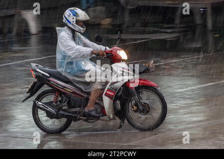 SAMUT PRAKAN, THAILANDIA, 03 ottobre 2023, autista di mototaxi in un giro in impermeabile sulla strada a causa di una pioggia intensa Foto Stock