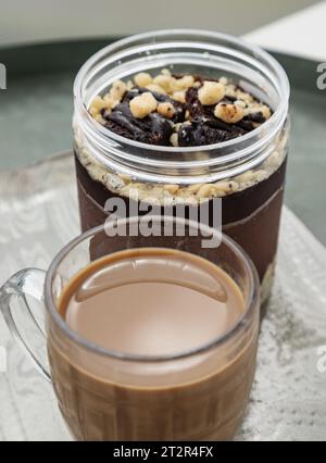 Brownie al cioccolato fondente croccante servito con caffè in una tazza di vetro. Il concetto di dessert delizioso, colazione, fuoco selettivo. Foto Stock