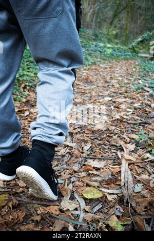 Piedi da uomo con scarpe sportive che camminano su un sentiero nella foresta Foto Stock