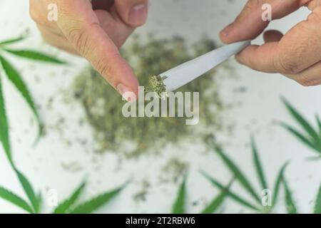 Close up di un uomo con le mani in mano fino al rotolamento di un giunto di marijuana Foto Stock