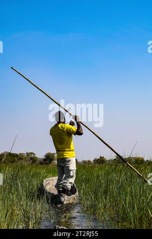 Un pescatore sta guidando con la sua barca attraverso il Delta dell'Okavango Foto Stock