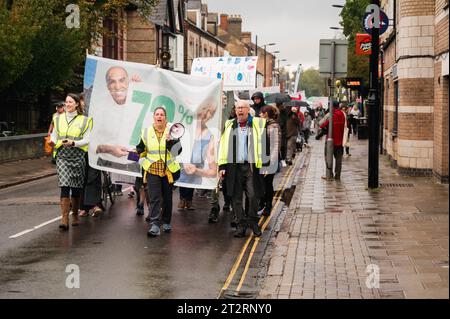 Cambridge, Regno Unito. 21 ottobre 2023. I residenti locali prendono parte a una danza a tema anni '1970 e marciano lungo Mill Road per chiedere l'introduzione di un cancello degli autobus per limitare i flussi di traffico nella strada della città. MillRoad4people sostiene che il 72% dei locali ha votato a favore del programma che ridurrebbe il flusso di veicoli sulla strada, ma non è stata ancora intrapresa alcuna azione per attuare i cambiamenti. Mill Road, che è composta da molti negozi indipendenti, aziende e aree residenziali, soffre di congestione del traffico. Crediti: Julian Eales/Alamy Live News Foto Stock