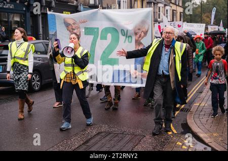 Cambridge, Regno Unito. 21 ottobre 2023. I residenti locali prendono parte a una danza a tema anni '1970 e marciano lungo Mill Road per chiedere l'introduzione di un cancello degli autobus per limitare i flussi di traffico nella strada della città. MillRoad4people sostiene che il 72% dei locali ha votato a favore del programma che ridurrebbe il flusso di veicoli sulla strada, ma non è stata ancora intrapresa alcuna azione per attuare i cambiamenti. Mill Road, che è composta da molti negozi indipendenti, aziende e aree residenziali, soffre di congestione del traffico. Crediti: Julian Eales/Alamy Live News Foto Stock