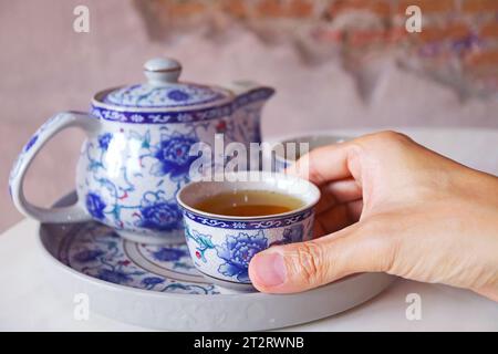 Primo piano della mano con una tazza di tè caldo cinese Oolong Foto Stock