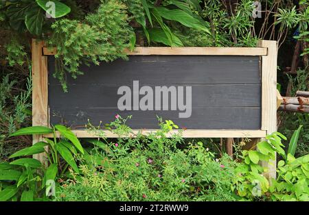 Lavagna in legno nero nel giardino con spazio per fotocopie Foto Stock
