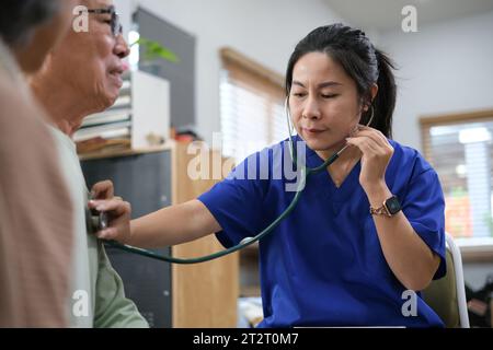 Medico attento o operatore sanitario che dà consigli professionali alla coppia anziana durante la visita a casa. Foto Stock