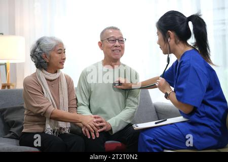 Medico attento o operatore sanitario che dà consigli professionali alla coppia anziana durante la visita a casa. Foto Stock