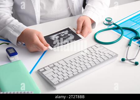 Medico femminile con immagine sonogramma alla scrivania medica bianca, primo piano Foto Stock