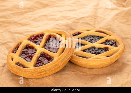 Due biscotti di frolla con marmellata su carta kraft, macro. Foto Stock