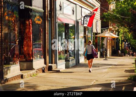 Una giovane donna passeggia davanti a affascinanti negozi di antiquariato e boutique nel pittoresco centro di Cold Spring New York Foto Stock