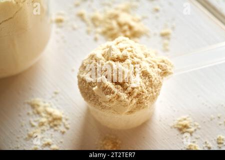 Polvere di proteine di siero di latte in un dosatore di plastica su un tavolo bianco Foto Stock