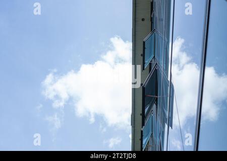Splendida ripresa dall'angolo basso di una finestra di un edificio alto e aperto, incorniciato da un bel cielo blu e soffici nuvole bianche Foto Stock