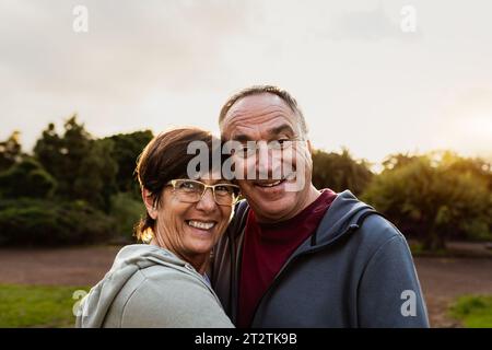 Felice coppia anziana che si diverte sorridendo nella telecamera dopo le attività di allenamento in un parco pubblico Foto Stock