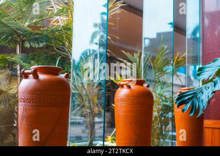 una collezione di caraffe artistiche marroni con squisite incisioni esposte vicino a una finestra di vetro Foto Stock