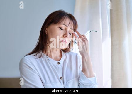 Donna di mezza età che soffre di stress, difficoltà, mal di testa Foto Stock