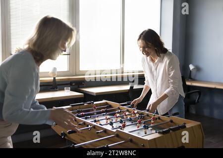 Due donne felici colleghi giocano a biliardino in ufficio Foto Stock