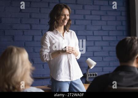 Una mentore sorridente fa una presentazione ai dipendenti dell'ufficio Foto Stock