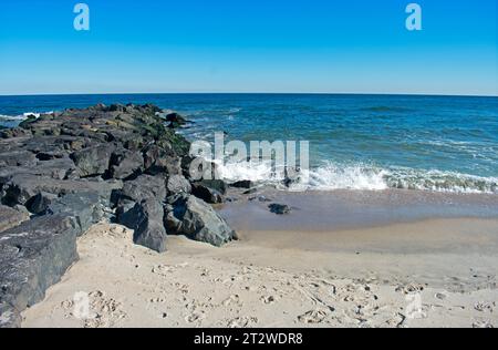 Il surf si schianta sulla riva e sul molo di roccia in una soleggiata giornata autunnale ad Asbury Park, New Jersey -02 Foto Stock