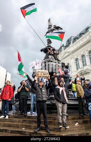 I giovani che protestano intorno alla statua di Eros, a Londra, con molte bandiere palestinesi e cartellone "bombardare i bambini non è autodifesa”. Foto Stock