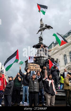 I giovani che protestano intorno alla statua di Eros, a Londra, con molte bandiere palestinesi e cartellone "bombardare i bambini non è autodifesa”. Foto Stock