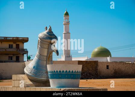 Un monumento a caraffa d'acqua con una moschea sullo sfondo a Mirbat, nel sud dell'Oman Foto Stock