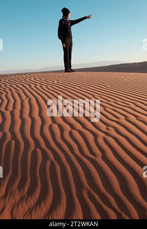 Una donna si trova sulle dune di sabbia ondulate delle Wahiba Sands nel deserto dell'Oman Foto Stock