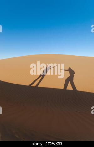 Gioco d'ombra tra due persone sulle dune di sabbia delle Wahiba Sands, nel deserto dell'Oman Foto Stock