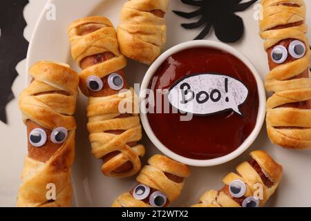 Gustose mummie di salsiccia per la festa di Halloween su piatto, vista dall'alto Foto Stock