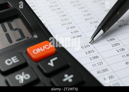 Calcolatrice e penna sul documento con calcoli finanziari, primo piano Foto Stock