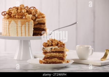 Goccia di caramello decorata con popcorn e pretzel serviti su un tavolo di marmo bianco Foto Stock