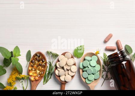 Pillole, erbe e fiori diversi su un tavolo di legno bianco, giacenza piatta con spazio per il testo. Integratori alimentari Foto Stock