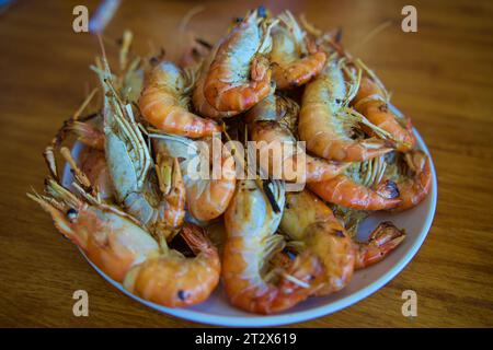 Grigliare grossi gamberi con sale e pepe su sfondo blu dall'alto. Deliziosi gamberetti alla griglia preparati al momento serviti sulla vista superiore del piatto Foto Stock