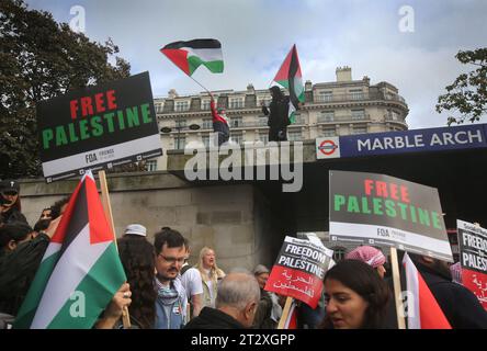 I manifestanti sventolano bandiere palestinesi sul tetto della stazione della metropolitana di Marble Arch. I sostenitori della Palestina si riuniscono per marciare verso Downing Street a seguito dei bombardamenti israeliani e della minaccia di un'invasione terrestre a Gaza da parte delle forze israeliane. Questa è la seconda settimana consecutiva che più di 100.000 persone sono scese per le strade di Londra per protestare. Molte delle organizzazioni coinvolte chiedono un cessate il fuoco, l'apertura del valico di Rafah in Egitto e la concessione di aiuti umanitari nella Striscia di Gaza. Foto Stock