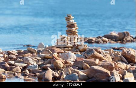 Una piramide di ciottoli sulla costa, sullo sfondo del mare Foto Stock