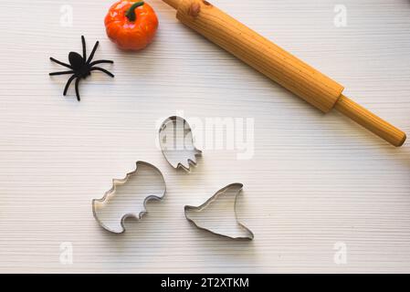 Preparare biscotti per Halloween. Una donna taglia i biscotti dall'impasto sotto forma di zucca, gatto, fantasma e pipipistrello Foto Stock