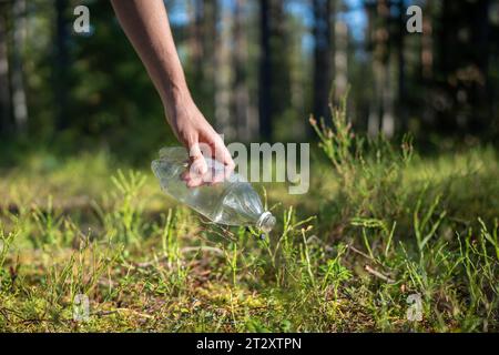 Attivista eco nella foresta trova rifiuti lasciati indietro, raccoglie bottiglie di plastica per preservare l'ambiente pulito Foto Stock